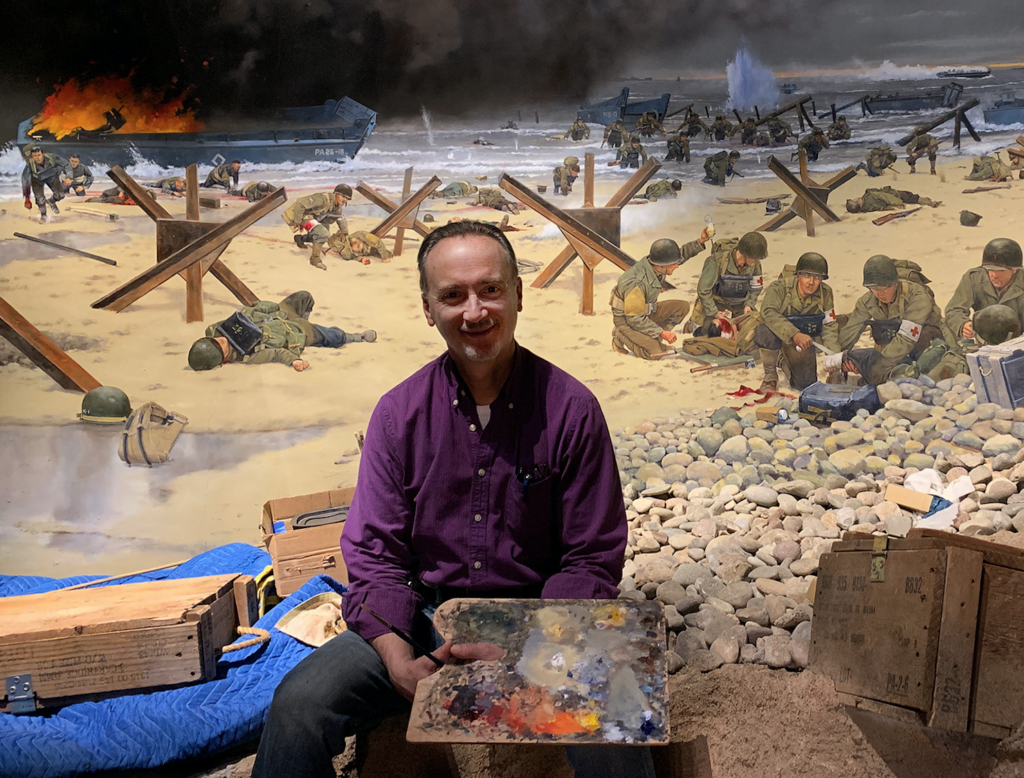 Keith Rocco in front of a section of his June 6 mural.